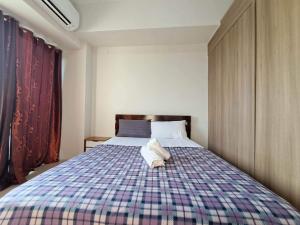 a bedroom with a large bed with a plaid blanket at Elresa Elegant at Field Residences Condominium Hotel in Manila +11 photos