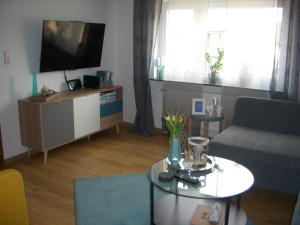 a living room with a couch and a table and a tv at Ferienwohnung RheinSpaziert in Dellhofen