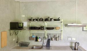 una cucina con lavandino e scaffali con pentole e padelle di PHUKET THALANG POOL VILLA a Thalang