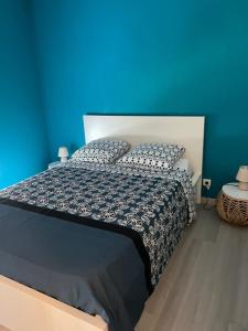 een slaapkamer met een bed met een blauwe muur bij appartement vacances en copropriété avec parking in Saint-Malo