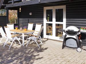 een grill op een patio met een tafel en stoelen bij 6 person holiday home in R m in Vesterhede