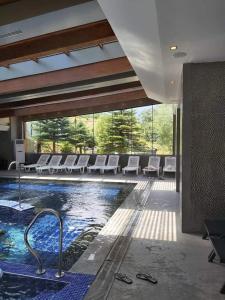 班斯科的住宿－Bansko St Ivan Rilski Luxury Apartment 4 stars Free SPA & Mineral water，一座带白色椅子的建筑中的游泳池