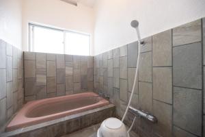 a bathroom with a pink tub and a toilet at BLUE MOON in Kawazu