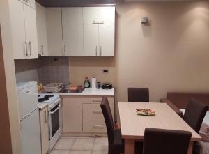 eine Küche mit einem Tisch und eine Küche mit weißen Schränken in der Unterkunft Apartment Spens in Novi Sad