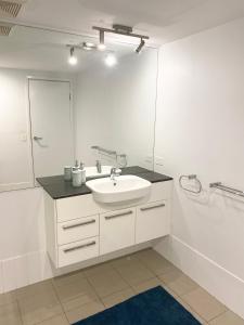 a white bathroom with a sink and a mirror at Cozy Cool Getaway in Townsville