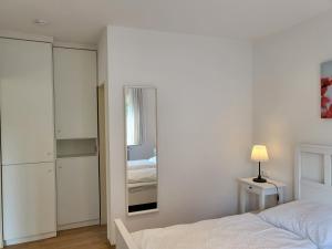 a white bedroom with a bed and a mirror at Ferienhaus Op de Diek in Ording