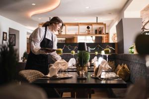 a woman standing in a room with a table at Alpin Boutique Villa Gabriela - Adults Only in Castelrotto