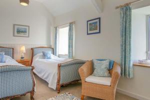 a bedroom with two beds and a chair and a window at Compass Cottage in Abersoch