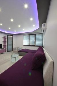 ヴェリコ・タルノヴォにあるApartment Relaxのリビングルーム(紫色のベッド1台、テーブル付)