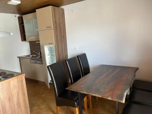 cocina con mesa de madera y sillas negras en Apartmaji Seljak, en Preddvor