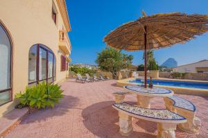 a patio with a table and an umbrella next to a pool at Villa Lina - PlusHolidays in Calpe