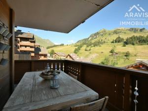 a wooden table on a balcony with a view of a mountain at Appartement Le Grand-Bornand, 3 pièces, 4 personnes - FR-1-391-5 in Le Grand-Bornand