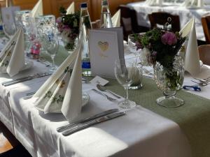 einen Tisch mit weißen Tischdecken, Servietten und Blumen in der Unterkunft Alter Wirt Ramersdorf in München