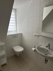 a white bathroom with a toilet and a sink at Alter Wirt Ramersdorf in Munich
