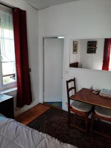 Zimmer mit einem Tisch, einem Stuhl und einer Tür in der Unterkunft Chambre Eugénie in Saint-Cloud