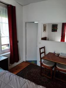 une chambre avec une table, une chaise et une porte dans l'établissement Chambre Eugénie, à Saint-Cloud