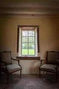 2 sillas sentadas en una habitación con ventana en Charnay Mery , une exceptionnelle maison de vacances au calme côté forêt avec piscine, en Vierzon