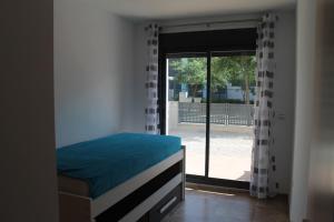 sypialnia z łóżkiem i przesuwanymi szklanymi drzwiami w obiekcie Appartement tout confort, Rez-de chaussée,3 chambres, 2 salles de bain w mieście Sant Jordi