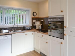 a kitchen with white cabinets and a sink at Elmbank in Lochcarron