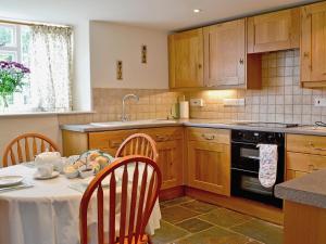 una cucina con tavolo e sedie e una cucina con piano cottura di Nightingales a Kentisbeare