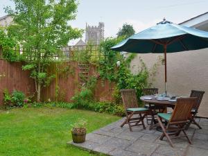 a table and chairs with an umbrella in a backyard at Nightingales in Kentisbeare