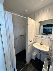 een witte badkamer met een wastafel en een douche bij Hotel Huys ter Schelde in Koudekerke