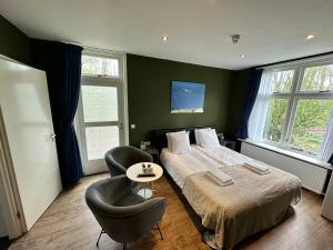 1 Schlafzimmer mit einem Bett und 2 Stühlen in der Unterkunft Hotel Huys ter Schelde in Koudekerke