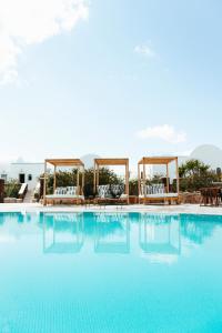 a large swimming pool with chairs and a gazebo at Astro Palace Hotel & Suites in Fira