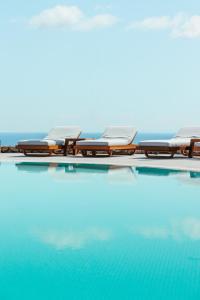 a row of chairs sitting next to a swimming pool at Astro Palace Hotel & Suites in Fira