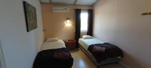 2 camas en una habitación pequeña con ventana en Villas del Alba, en Alhaurín de la Torre