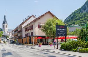 a street with a building and a sign in a town at Hôtel-Restaurant "Les Rochers" in La Balme-de-Sillingy