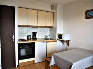 małą kuchnię z białymi szafkami i kuchenką mikrofalową w obiekcie Studio cabine fermée, 4 couchages, balcon ensoleillé, au pied des pistes - Auris en Oisans - FR-1-297-306 w mieście Auris