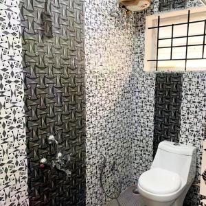 a bathroom with a toilet and black and white tiles at Kalyani Homestay in Kodaikānāl