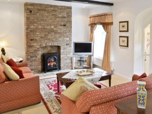 a living room with a fireplace and a tv at Gamekeepers Cottage in Middleton