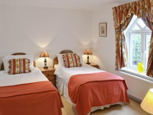 a bedroom with two beds and a window at Gamekeepers Cottage in Middleton
