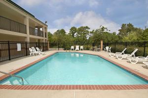 a large swimming pool with chairs and a table at Super 8 by Wyndham Slidell in Slidell