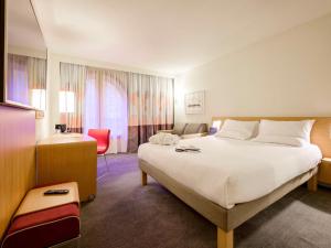 ein Hotelzimmer mit einem großen Bett und einem Schreibtisch in der Unterkunft Novotel Birmingham Centre in Birmingham