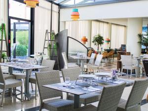 un restaurante con mesas, sillas y ventanas en ibis Styles Evry Courcouronnes Hotel and Events, en Courcouronnes