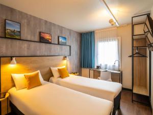 a hotel room with two beds and a desk at ibis Saint-Malo Madeleine in Saint Malo