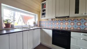 eine Küche mit weißen Schränken, einem Waschbecken und einem Fenster in der Unterkunft Salarpsgården in Hammenhög