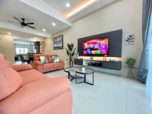 a living room with pink furniture and a flat screen tv at Langkawi Cozy Holiday Home at Desa Impian by Zervin in Kuah