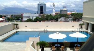 uma grande piscina com guarda-sóis num edifício em Braga City Walk Apartment 8th Floor - deNara em Bandung