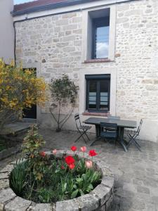 een patio met een tafel en bloemen voor een gebouw bij Chez Marylene in Soisy-sur-École