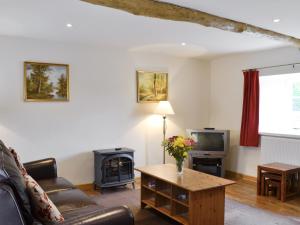 a living room with a couch and a table and a tv at The Old Stables in Sherston