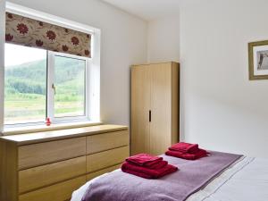 Duas toalhas vermelhas estão sentadas numa cama num quarto em Corrie Massan em Benmore