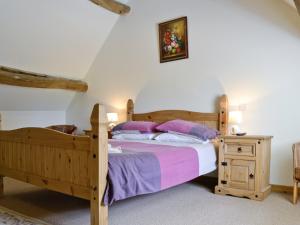 a bedroom with a wooden bed with purple pillows at The Old Stables in Sherston