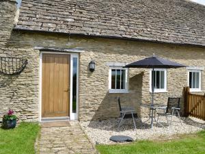 a stone cottage with a table and an umbrella at The Old Stables in Sherston