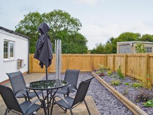 een patio met een tafel en stoelen en een hek bij Wold View in Gristhorpe