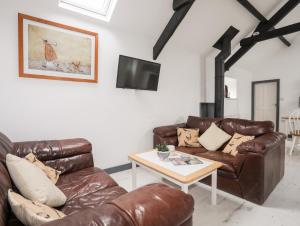 a living room with two brown leather couches and a table at Cowshed in Pwllheli