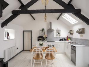 a kitchen with white cabinets and a table and chairs at Cowshed in Pwllheli